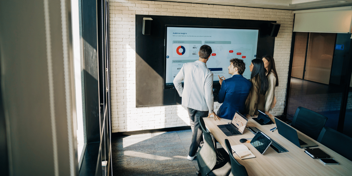 Business team reviewing audience insights and analytics on a large presentation screen.