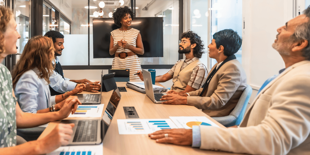 Business team listening to a colleague present during a meeting in a modern office.
