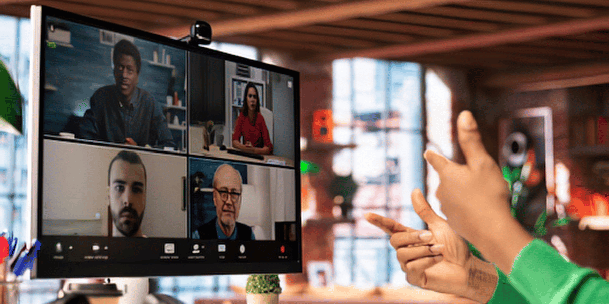 Professional collaborating with a remote team during a video meeting on a computer.