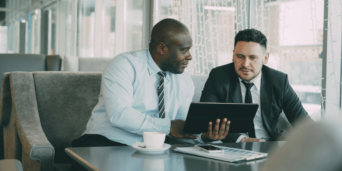 Two business professionals reviewing information together on a tablet during a meeting.