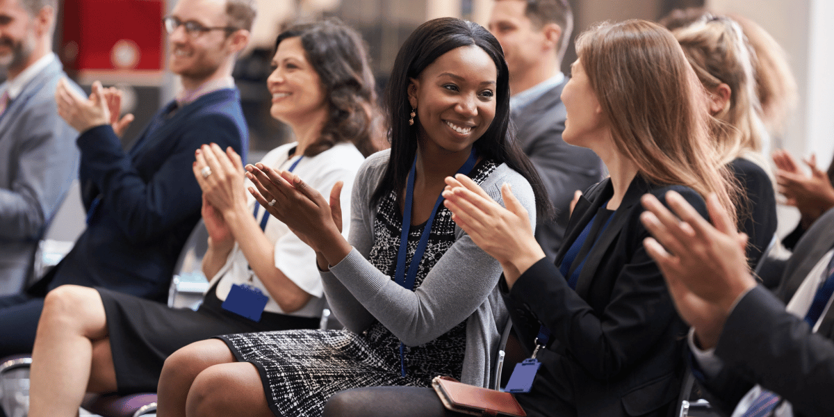 Business professionals applauding and networking during a conference event.