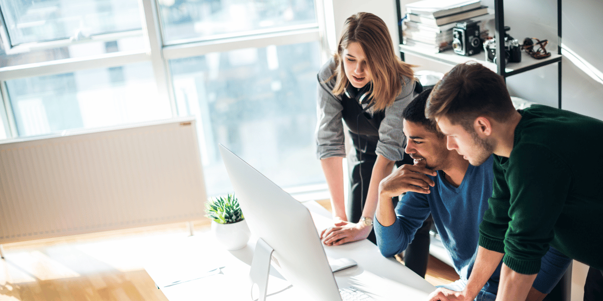 Small business team collaborating around a computer in a modern office.