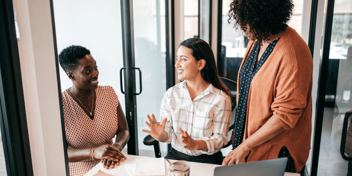 Three business professionals discussing HubSpot support options in a modern office.